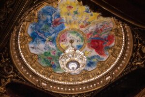 Exquisite fresco and chandelier at Palais Garnier in Paris, showcasing Neo-Baroque architecture and Chagall art.